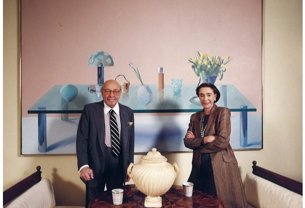 Mica and Ahmet Ertegun pose before David Hockney’s Still Life on a Glass Table from 1971 in their Manhattan residence.